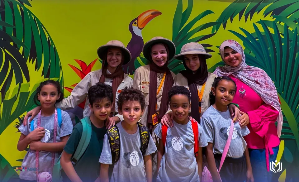 طلاب مع مرشدات يرتدين قبعات السفاري أمام جدارية الغابة