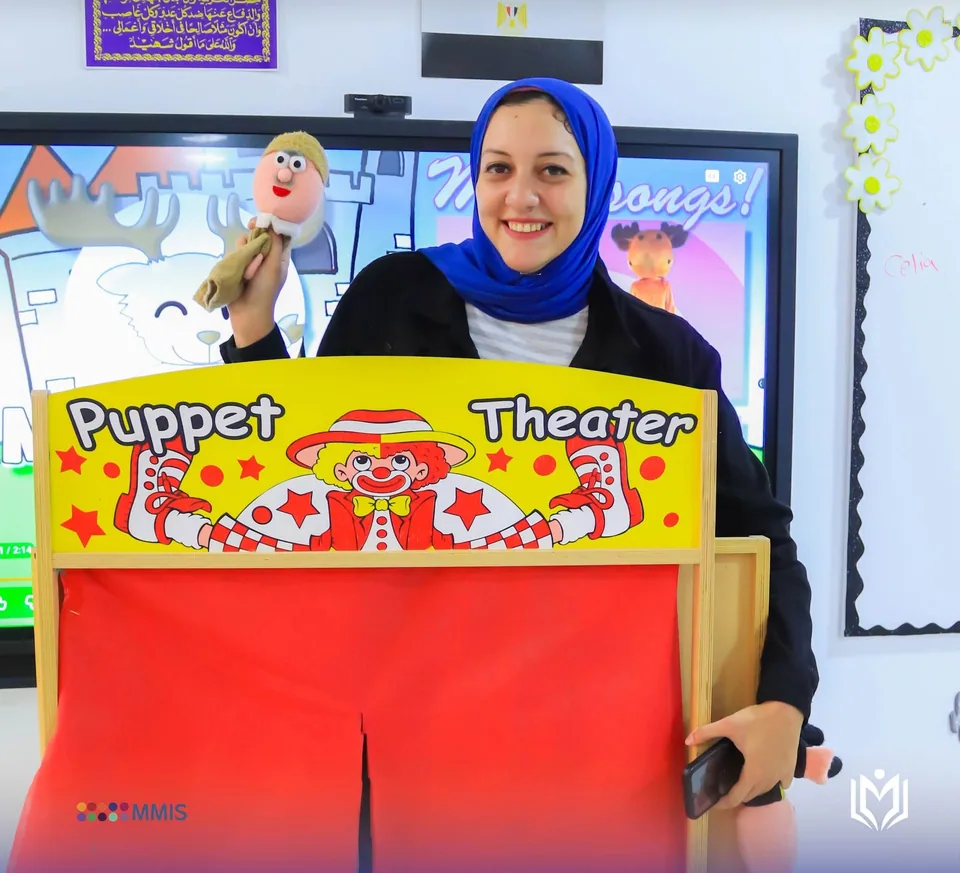 معلمة تحمل دمية يد خلف مسرح العرائس في الفصل