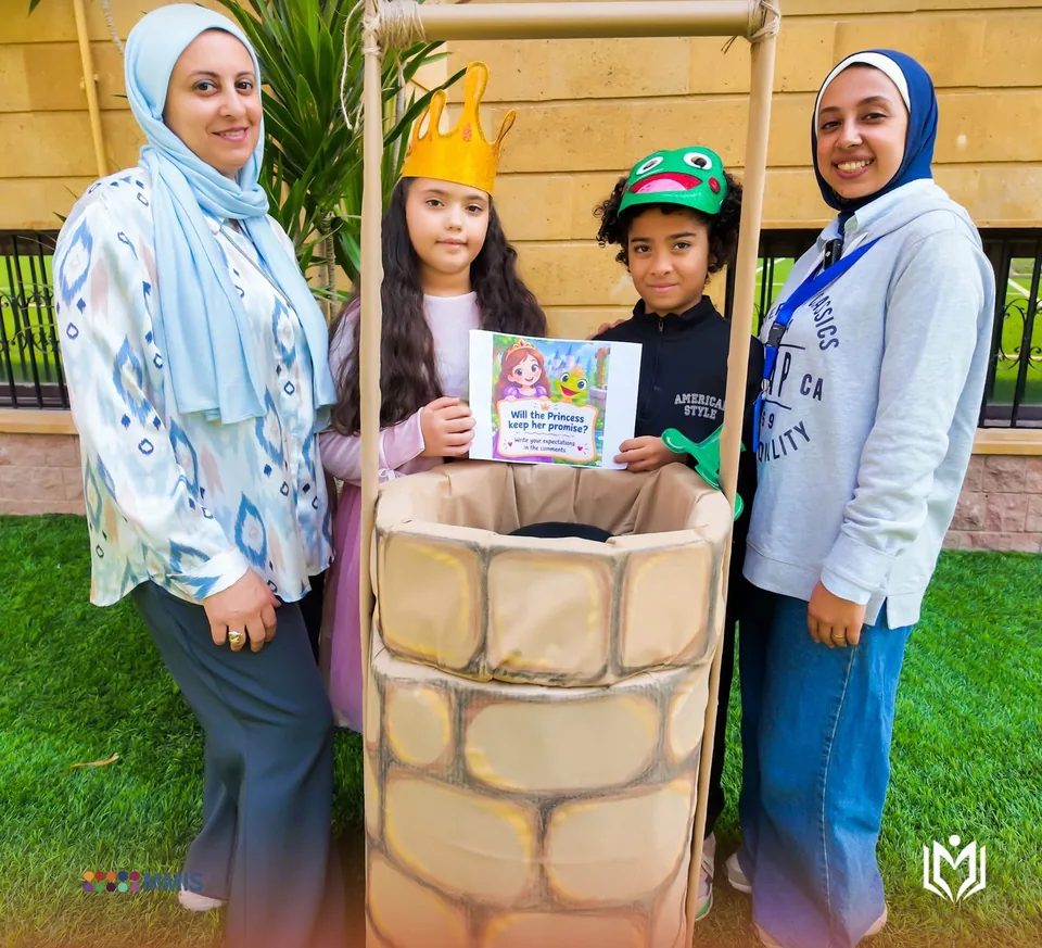 معلمتان مع طالبين بزي الأميرة والضفدع بجوار بئر من الكرتون